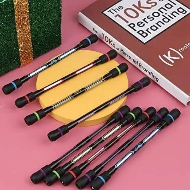 Set of pens with colorful accents on a pink surface next to a book titled 'The 10ks of Personal Branding'.