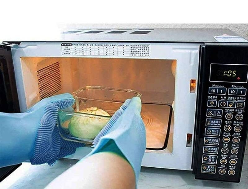 Person wearing gloves using a glass bowl inside an open microwave.