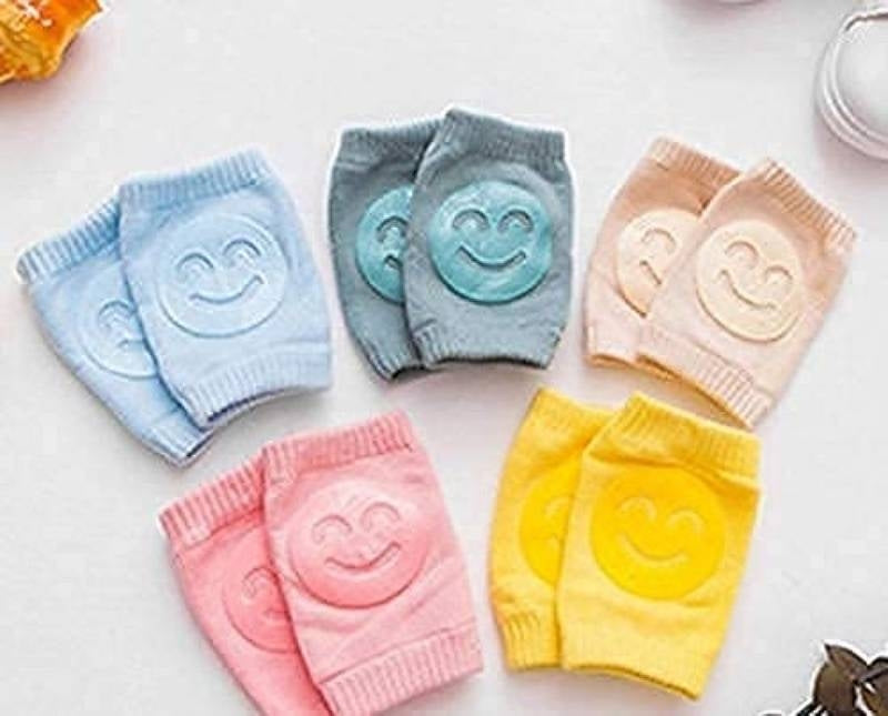 Set of colorful baby knee pads with smiley face designs on a light background