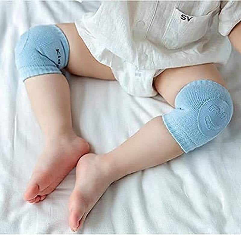 Baby wearing light blue knee pads on a white bed