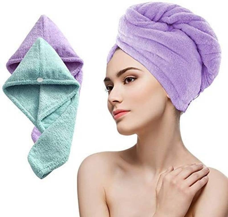 Woman wearing a purple towel on her head with a green towel beside her on a white background