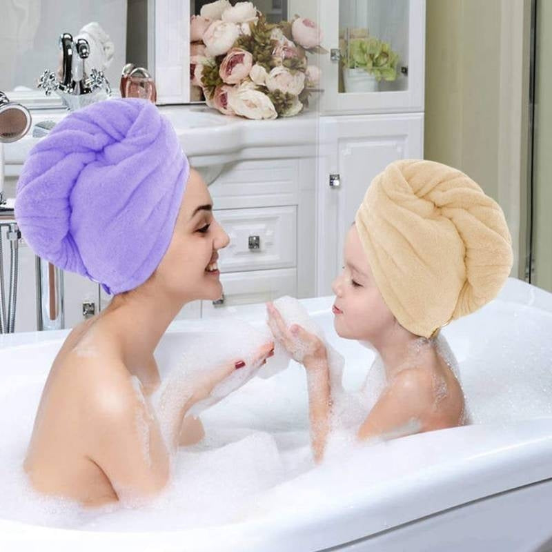 Woman and child in a bathtub with towel turbans on, surrounded by decorative flowers.