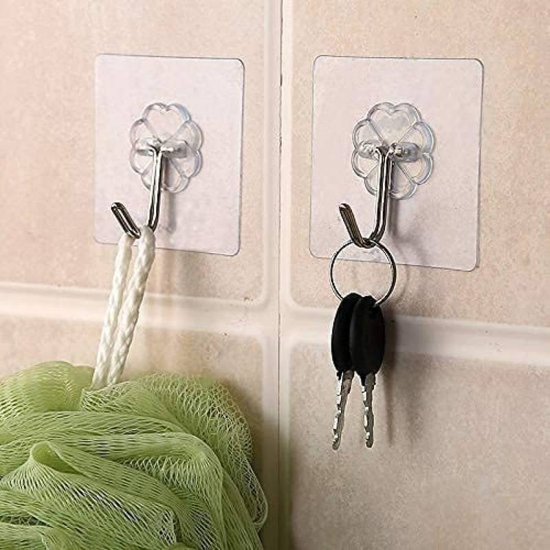 Clear adhesive hooks on a tiled wall with keys and a loofah.