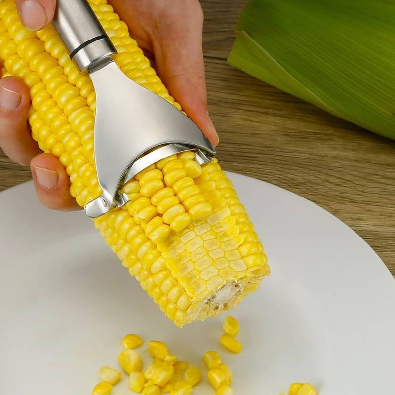 Corn on the cob being peeled with a corn peeler on a wooden surface.