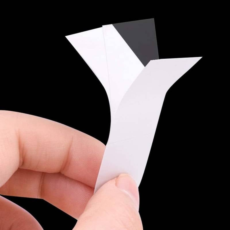 Hand holding a white plastic component against a black background