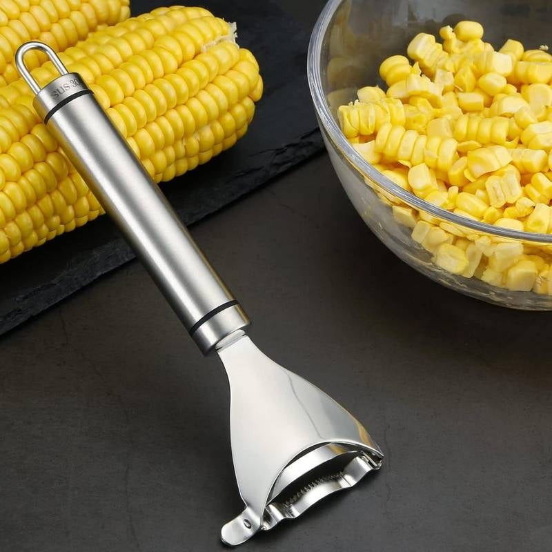 Corn sheller with corn on the cob and a bowl of corn kernels on a dark surface