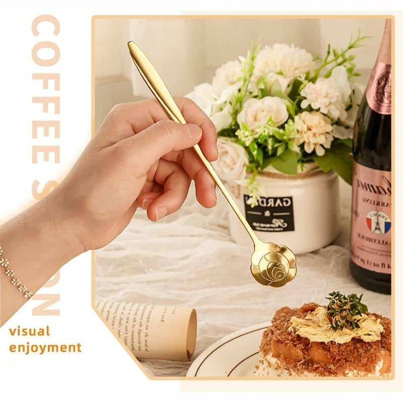Hand holding a gold spoon over a plate of food with a bottle and flowers in the background.