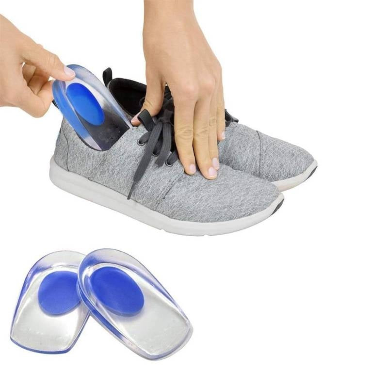 Person putting blue shoe inserts into a gray sneaker on a white background