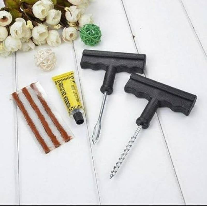 Two black squeegees and a tube of yellow cream on a white surface with flowers in the background.
