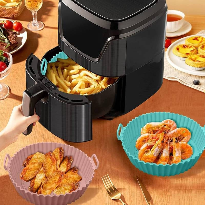 Black air fryer with cooked food on a wooden table