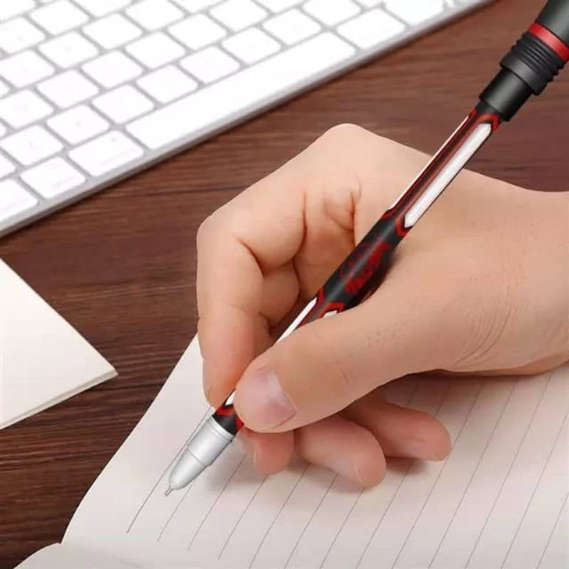 Hand holding a pen on a notebook with a keyboard in the background.