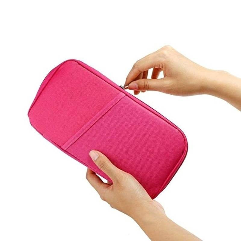 Pink travel organizer with hands holding it on a white background