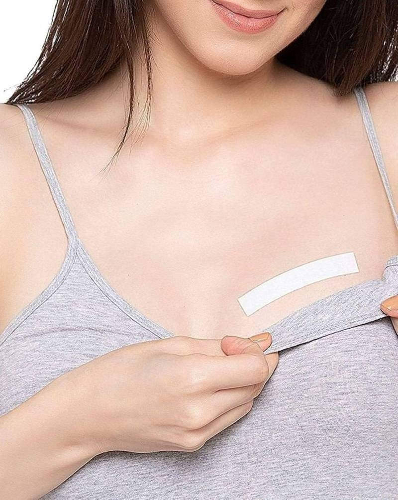 Woman applying a bandage to a small cut on her chest.